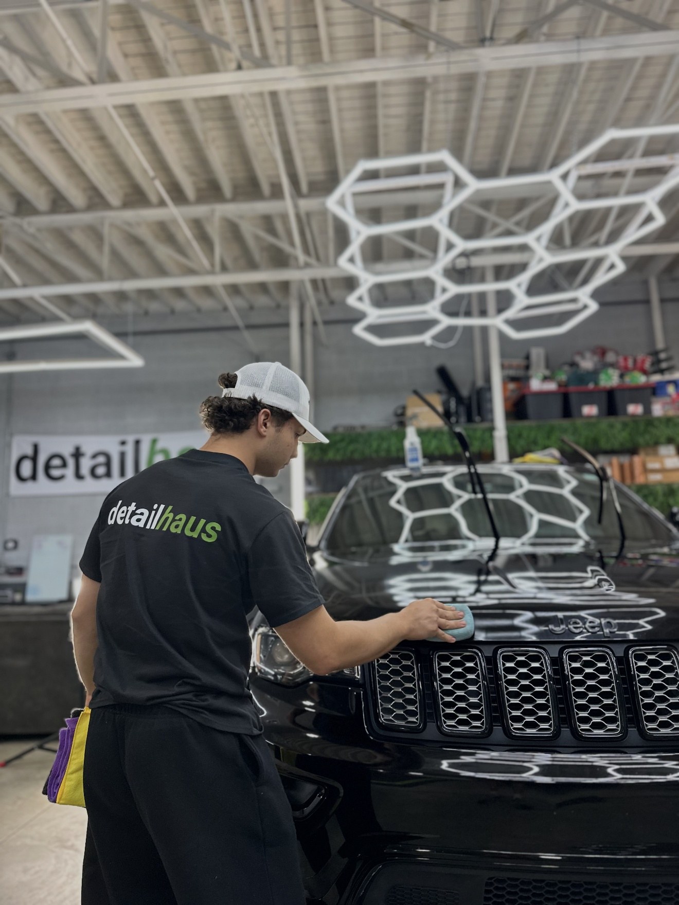 A DetailHaus technician hand-applying coating to a black Jeep in the Ansonia studio