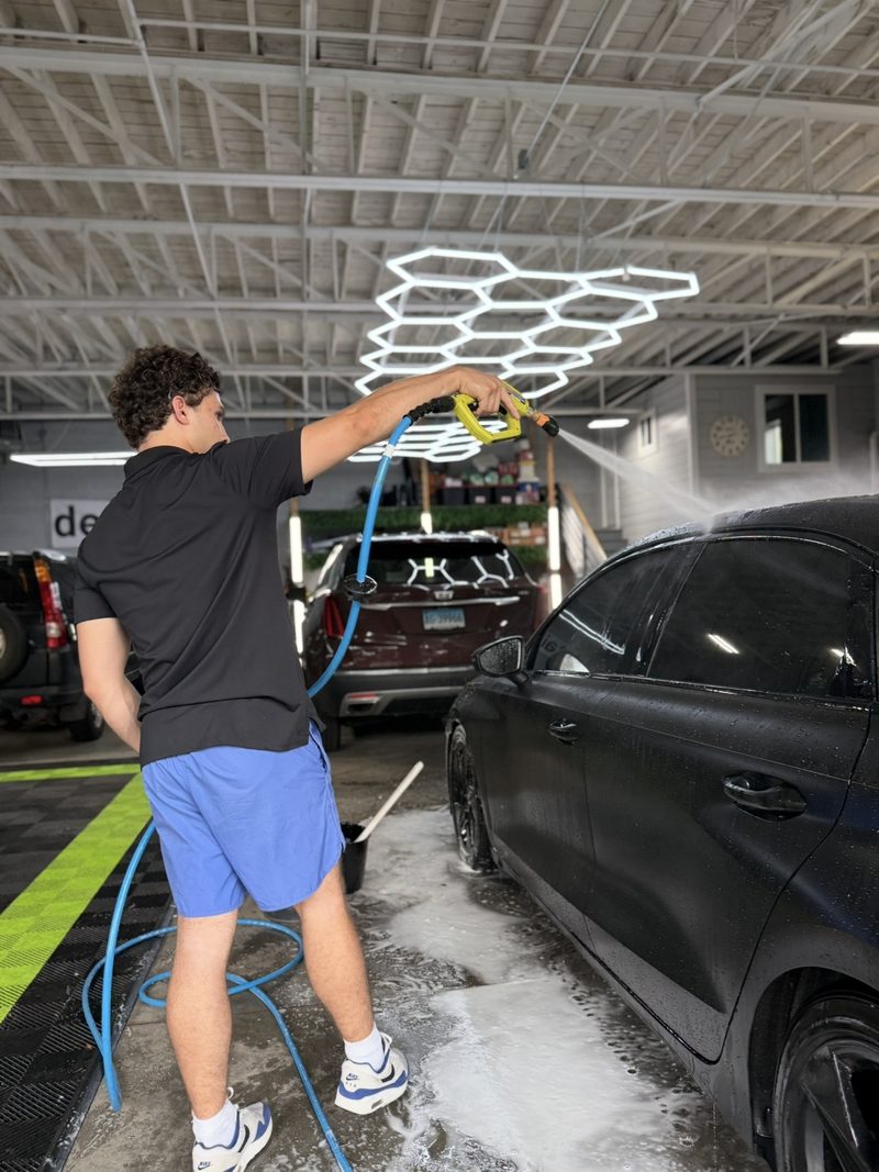 Hand washing a matte black car at the DetailHaus studio