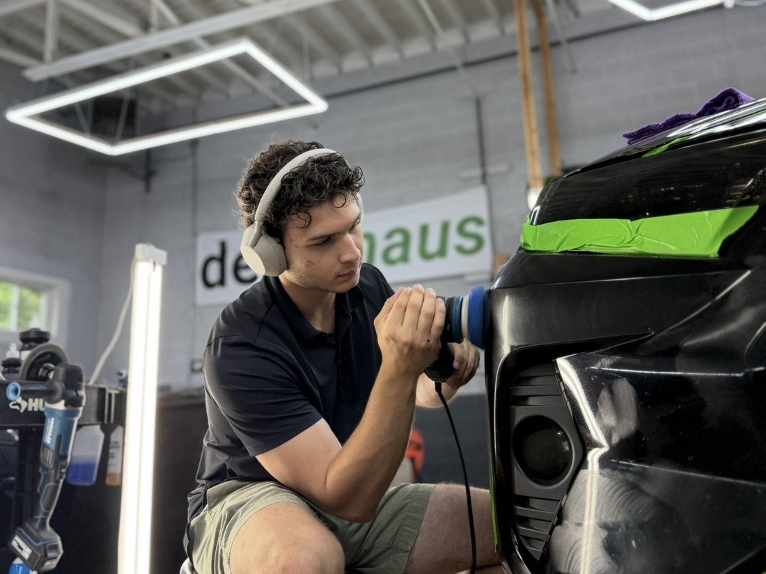 Machine polishing a black vehicle during paint correction at DetailHaus